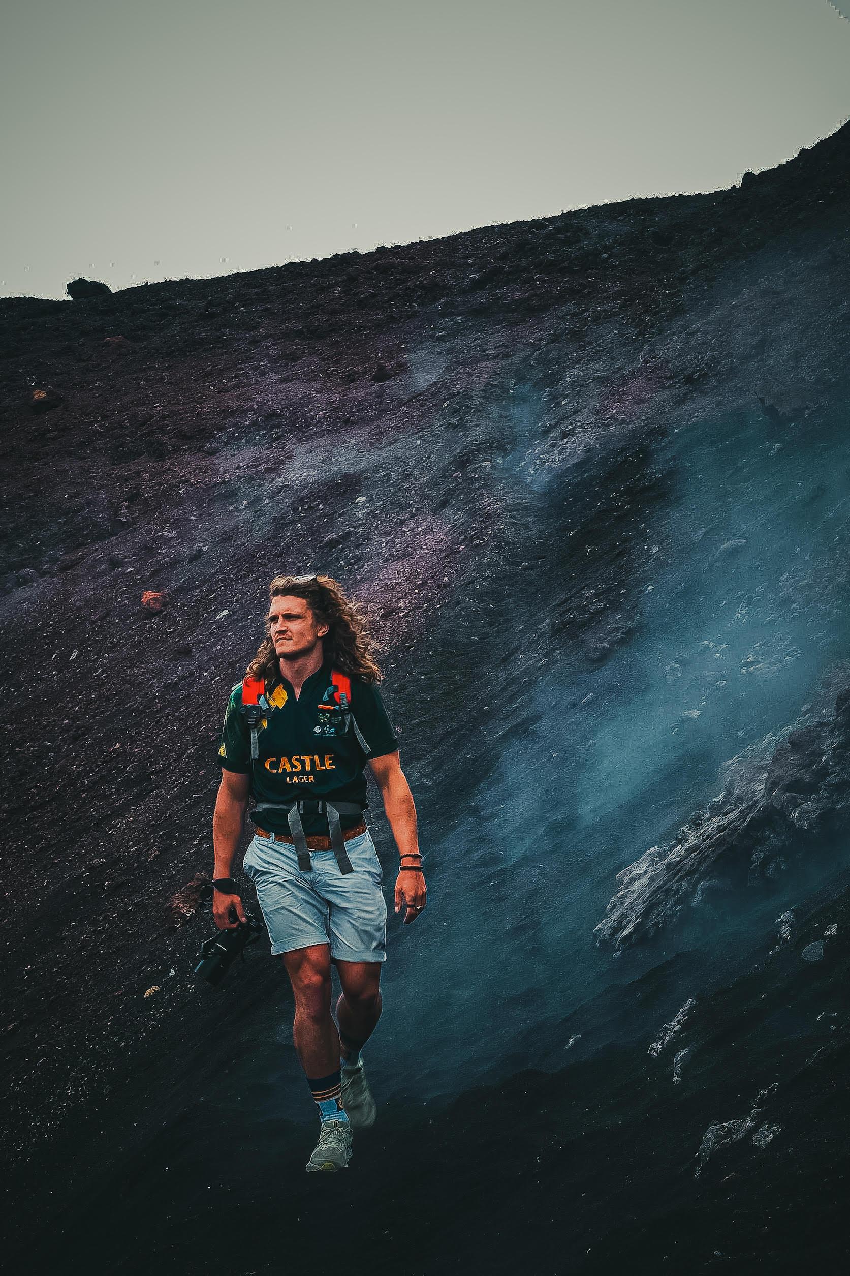 Photographer walking down a volcanic slope with a camera in hand
