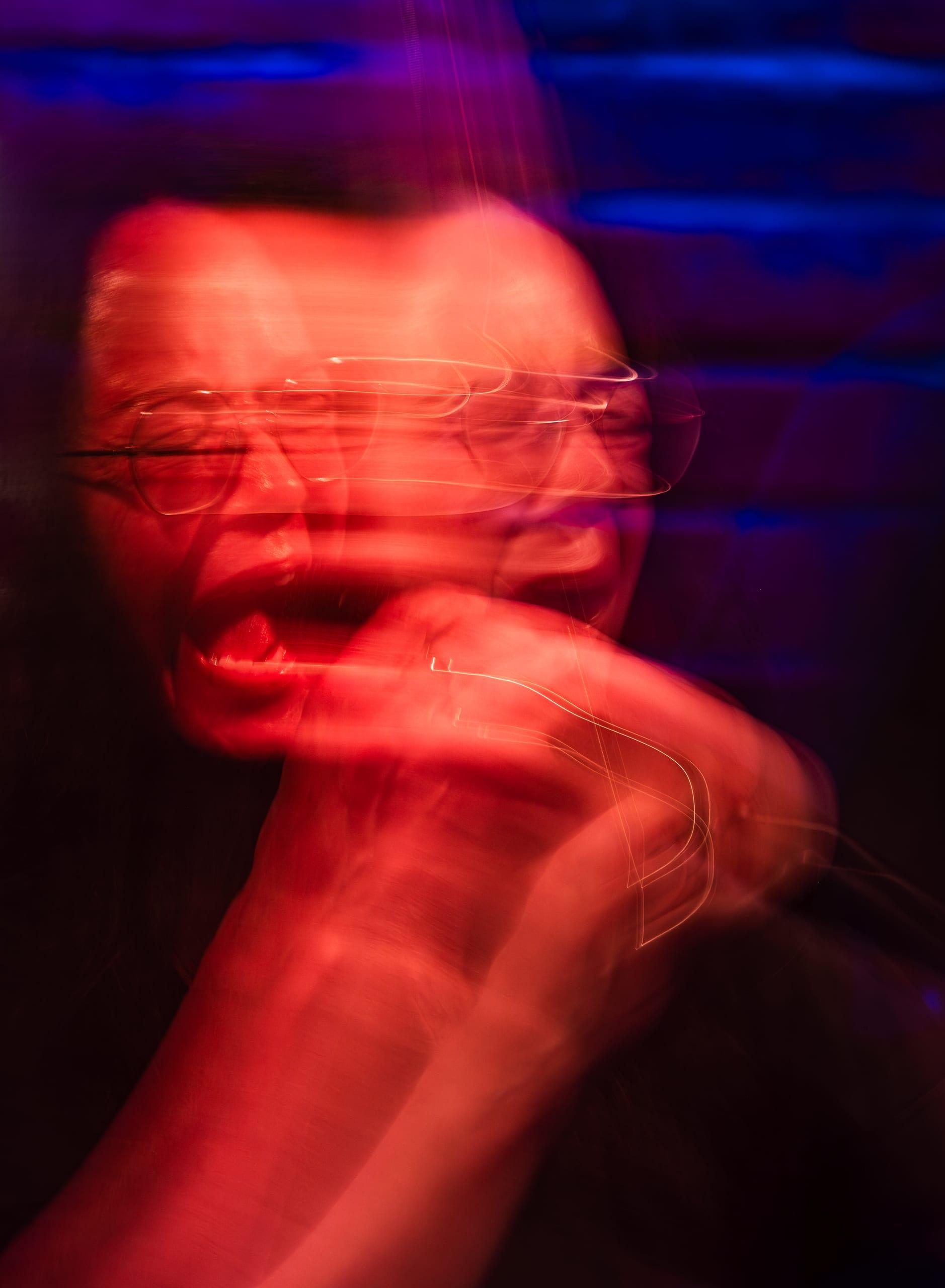 Long exposure of the singer mid-note, features trailing with motion