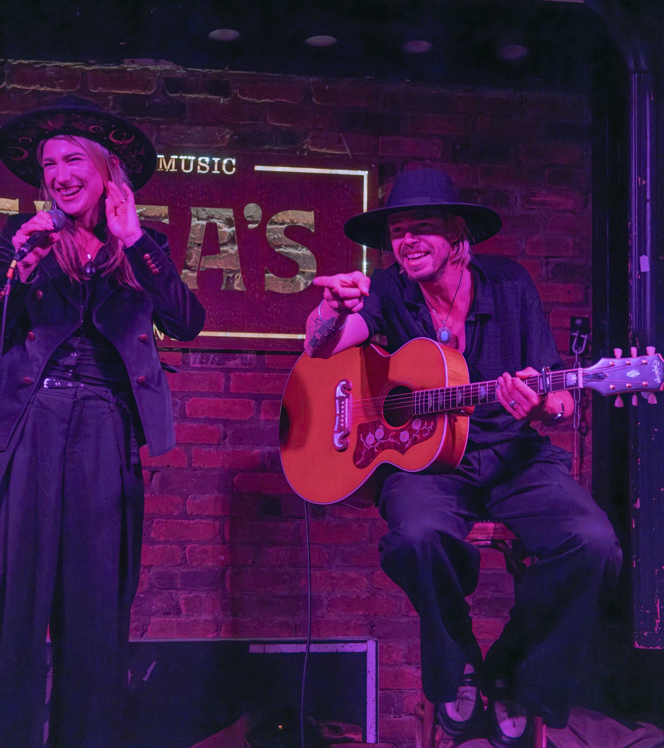 Singer and guitarist laughing together mid-set