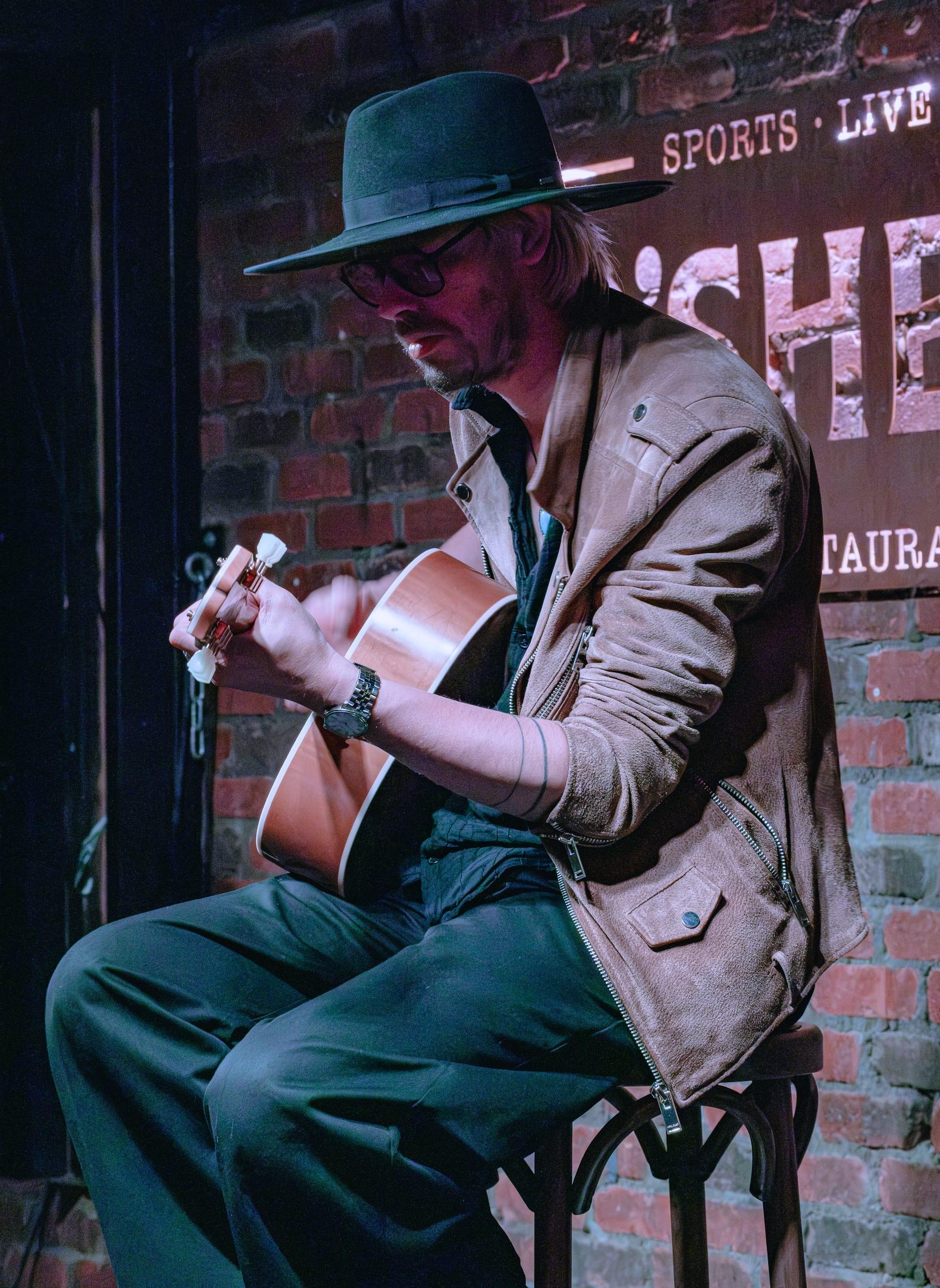 Guitarist tuning his instrument between songs, warm stage light