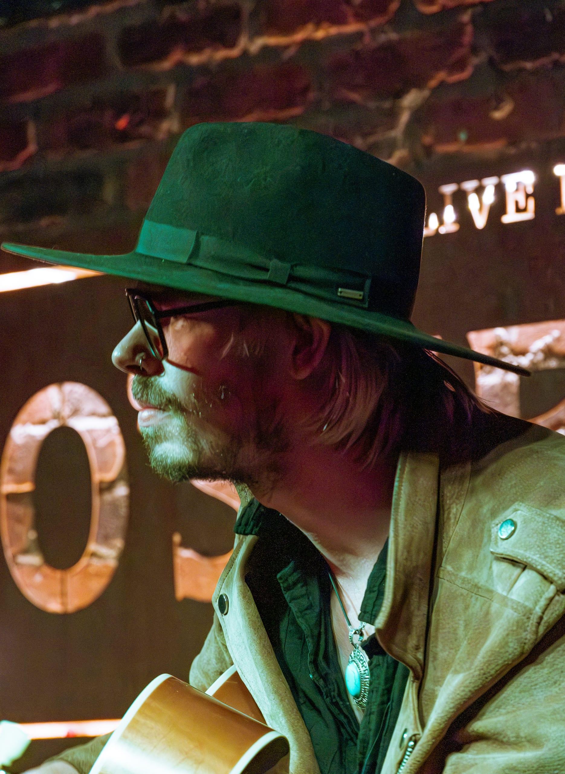 A second musician in profile, glasses catching the stage light