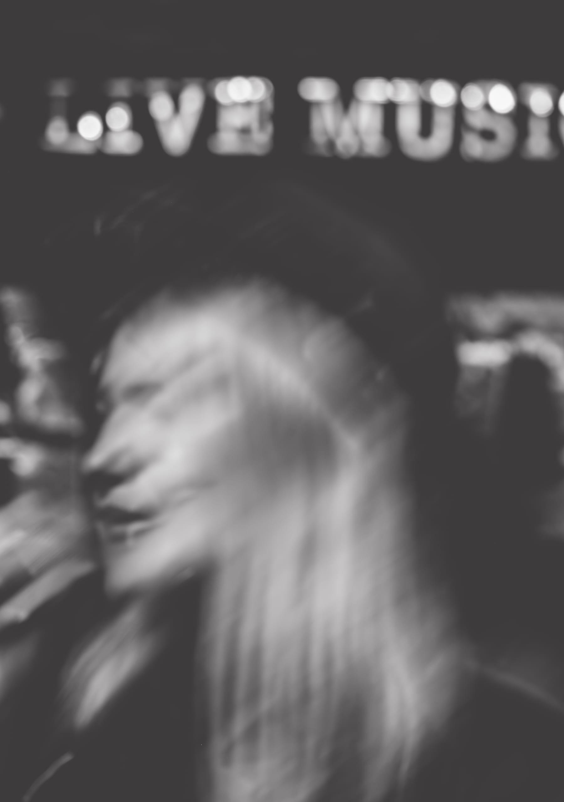 Long exposure black and white blur of the singer turning, LIVE MUSIC sign visible above