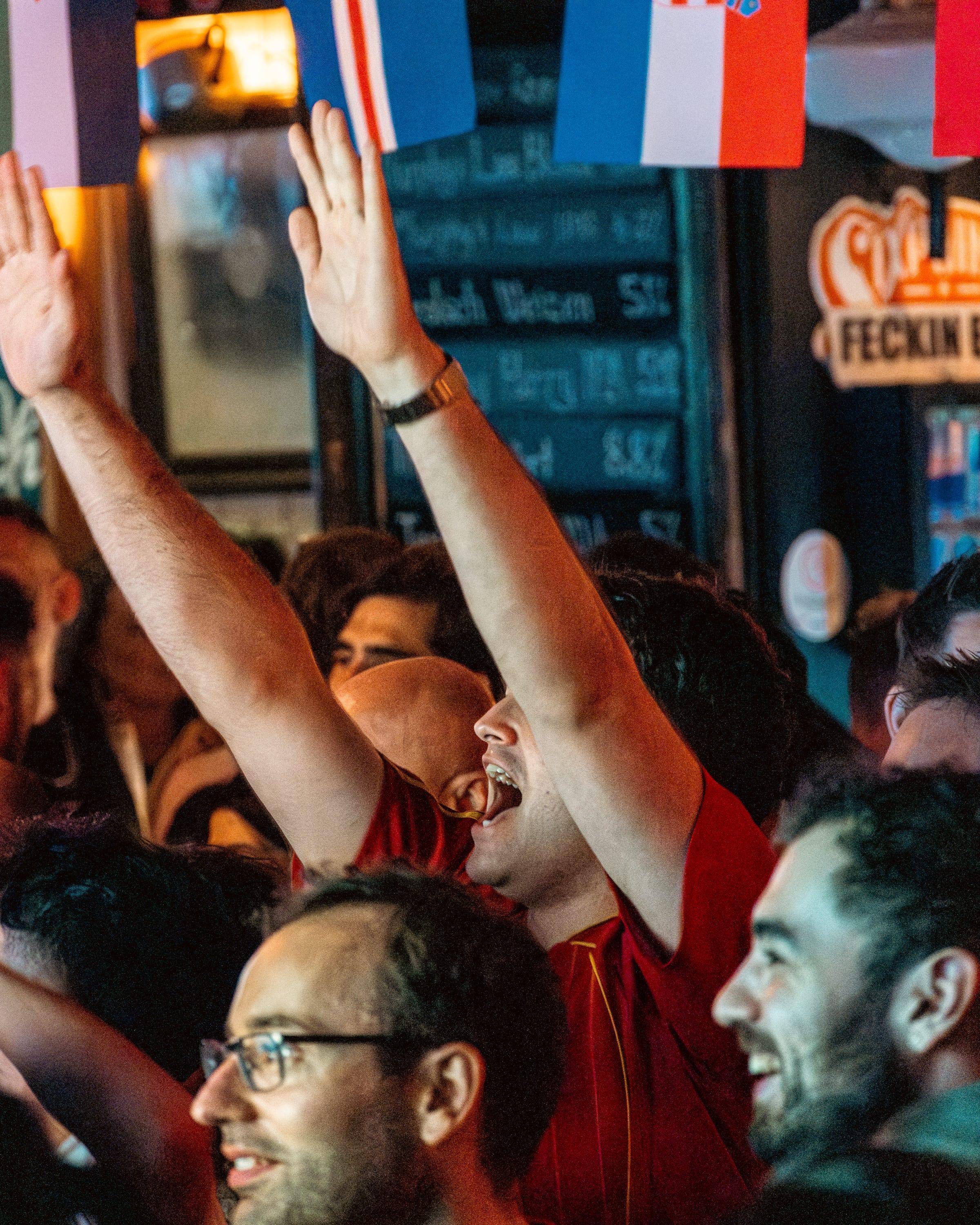 Arms thrown up in a red España shirt, French flags strung overhead