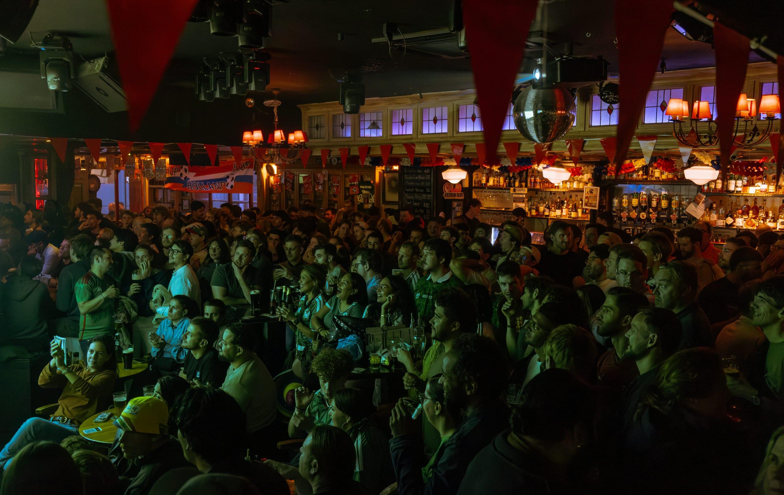 Packed pub under red bunting and a disco ball, the room turned toward the match