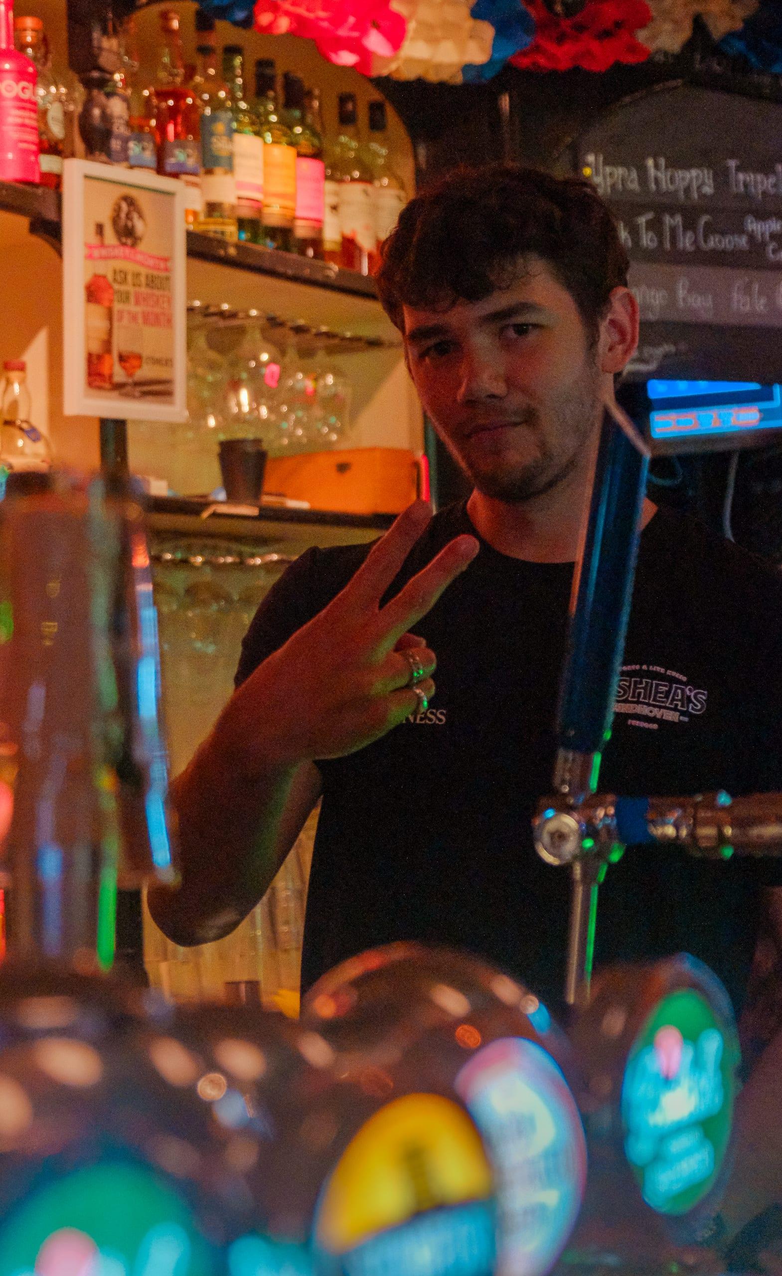 O'Shea's bartender behind the taps, peace sign, mid-service