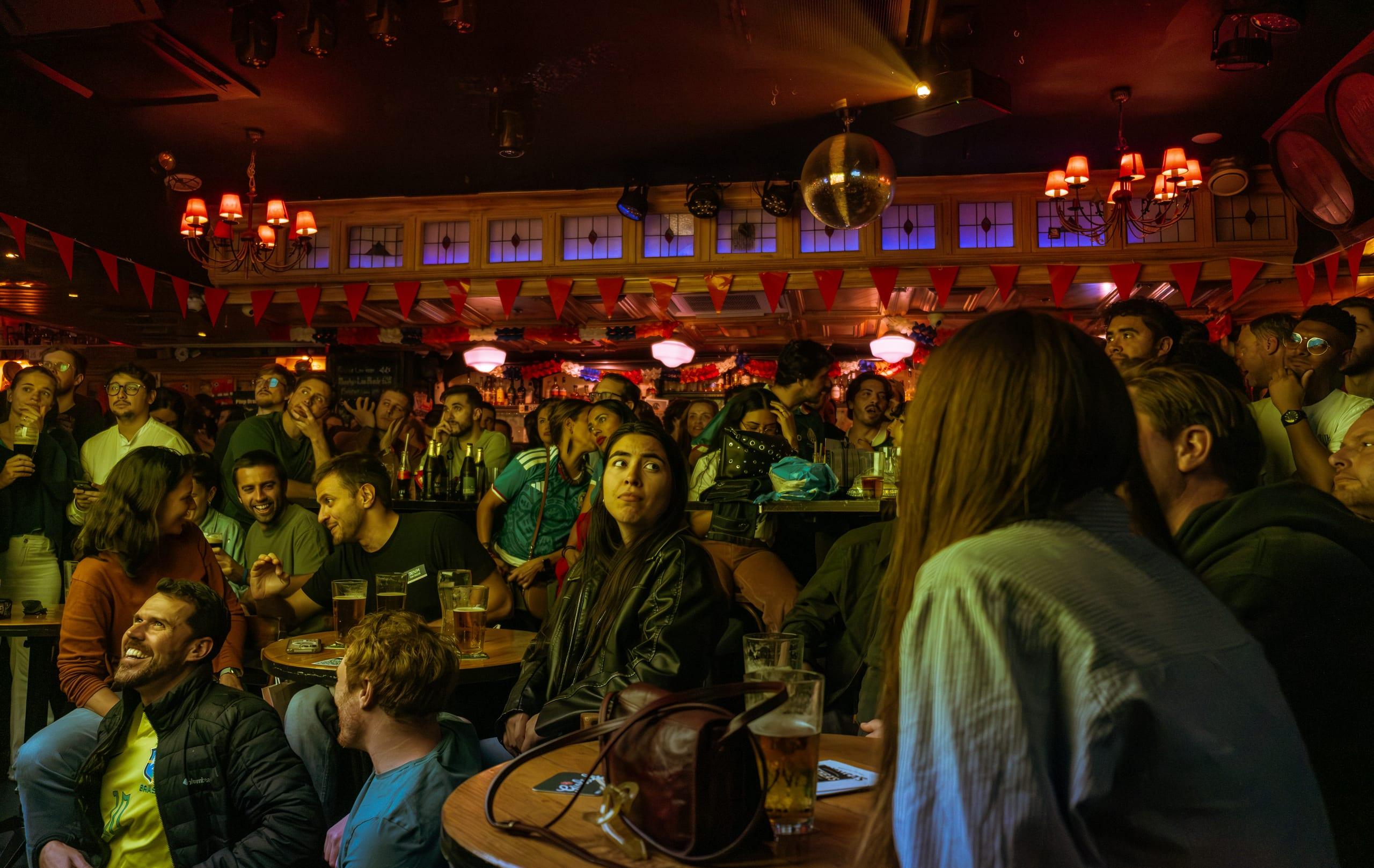 Crowd packed round the tables, all eyes lifted to the screen