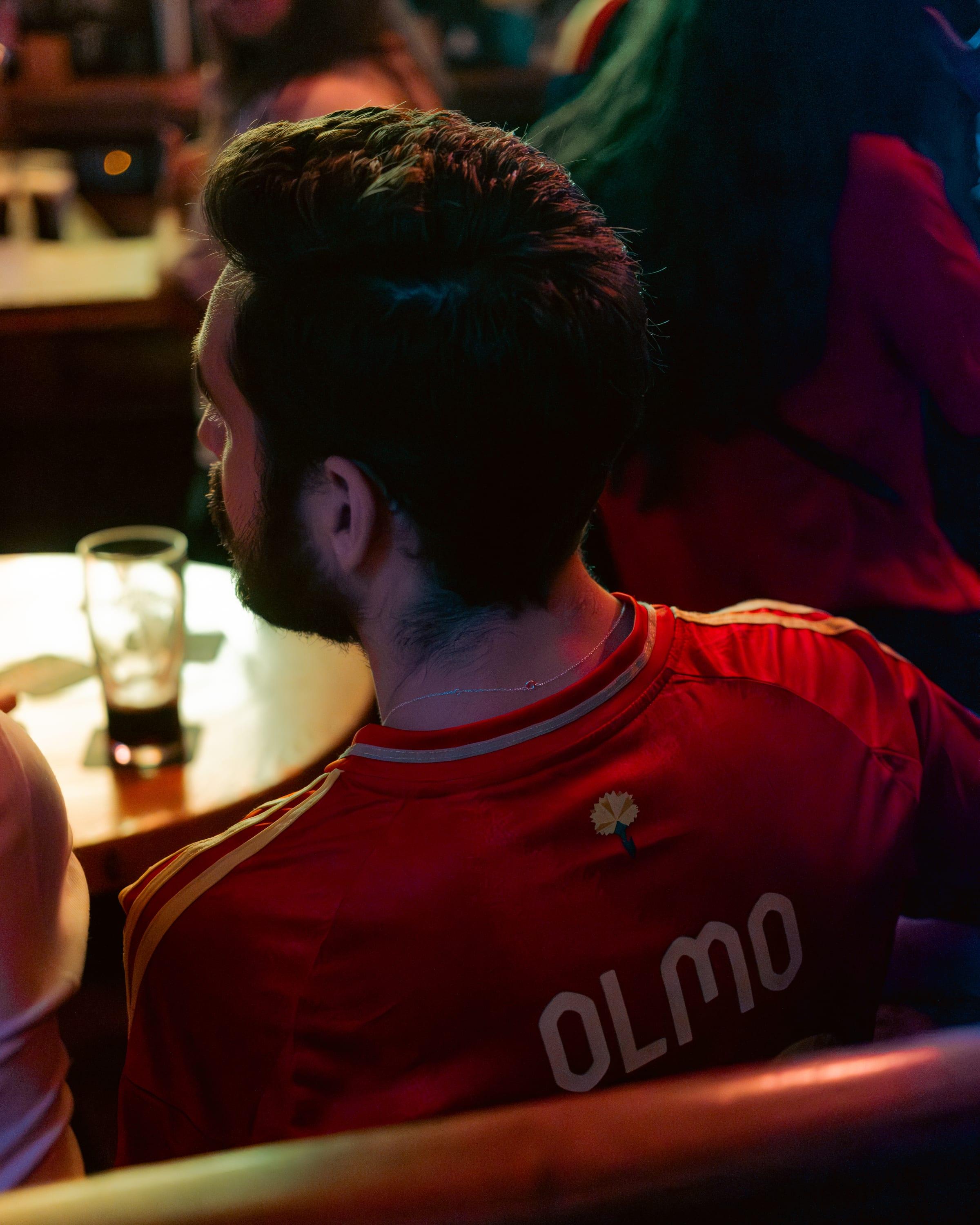Close detail of a Spain shirt reading Olmo, a dark pint glowing under a lamp