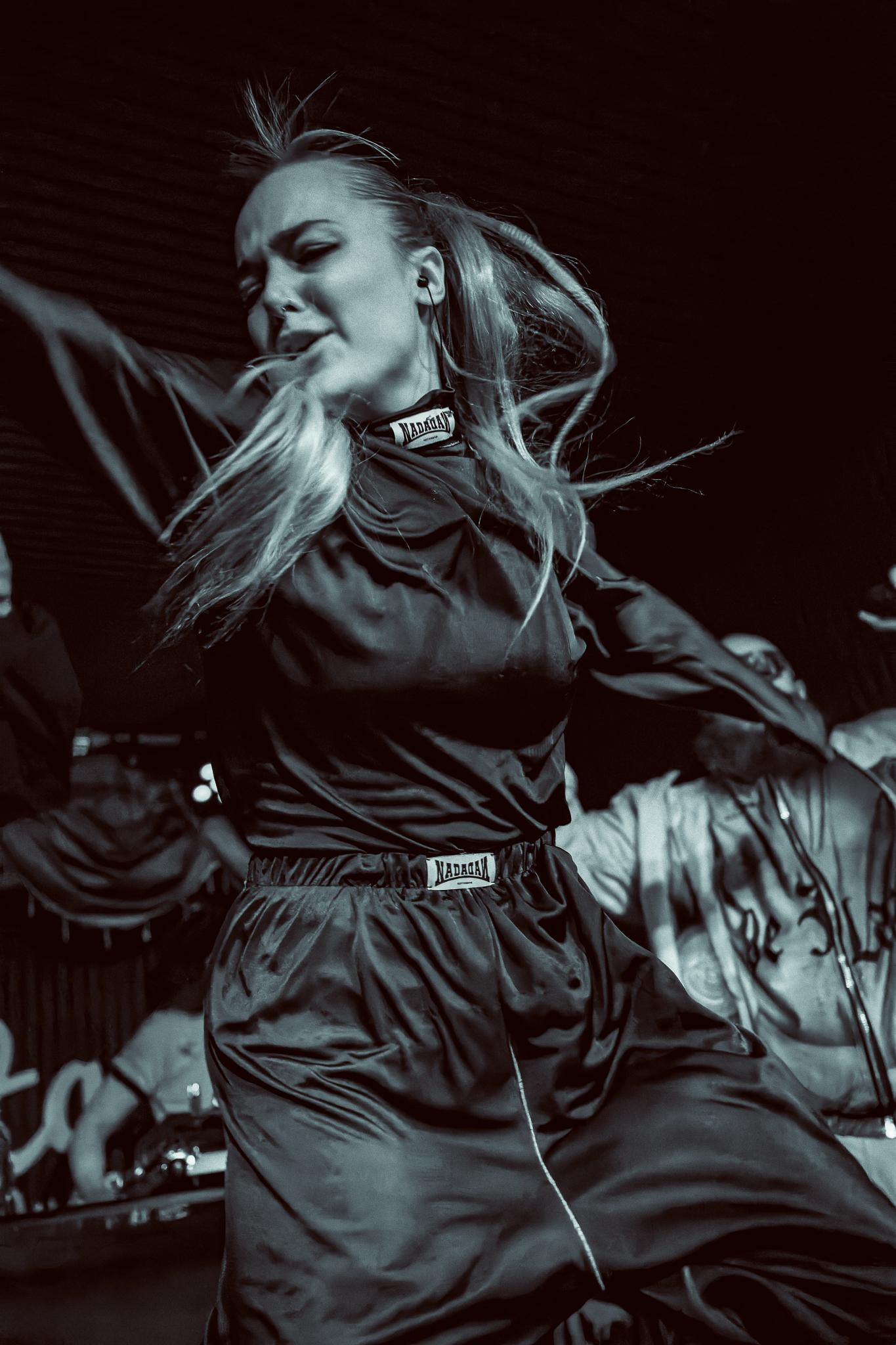 A dancer caught mid-turn, hair flying, dressed in a dark flowing outfit, black and white
