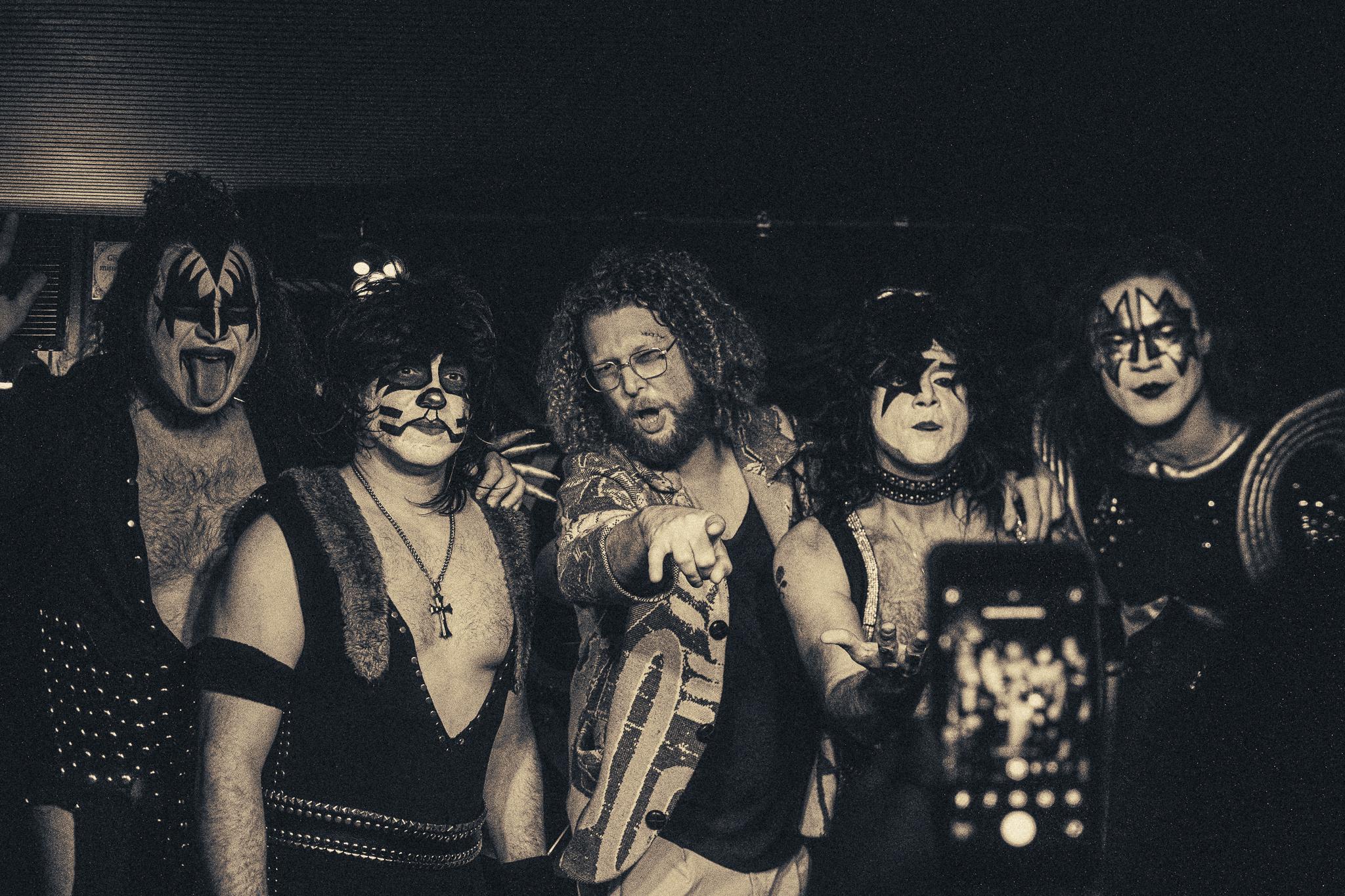 A KISS tribute band posing together backstage, black and white