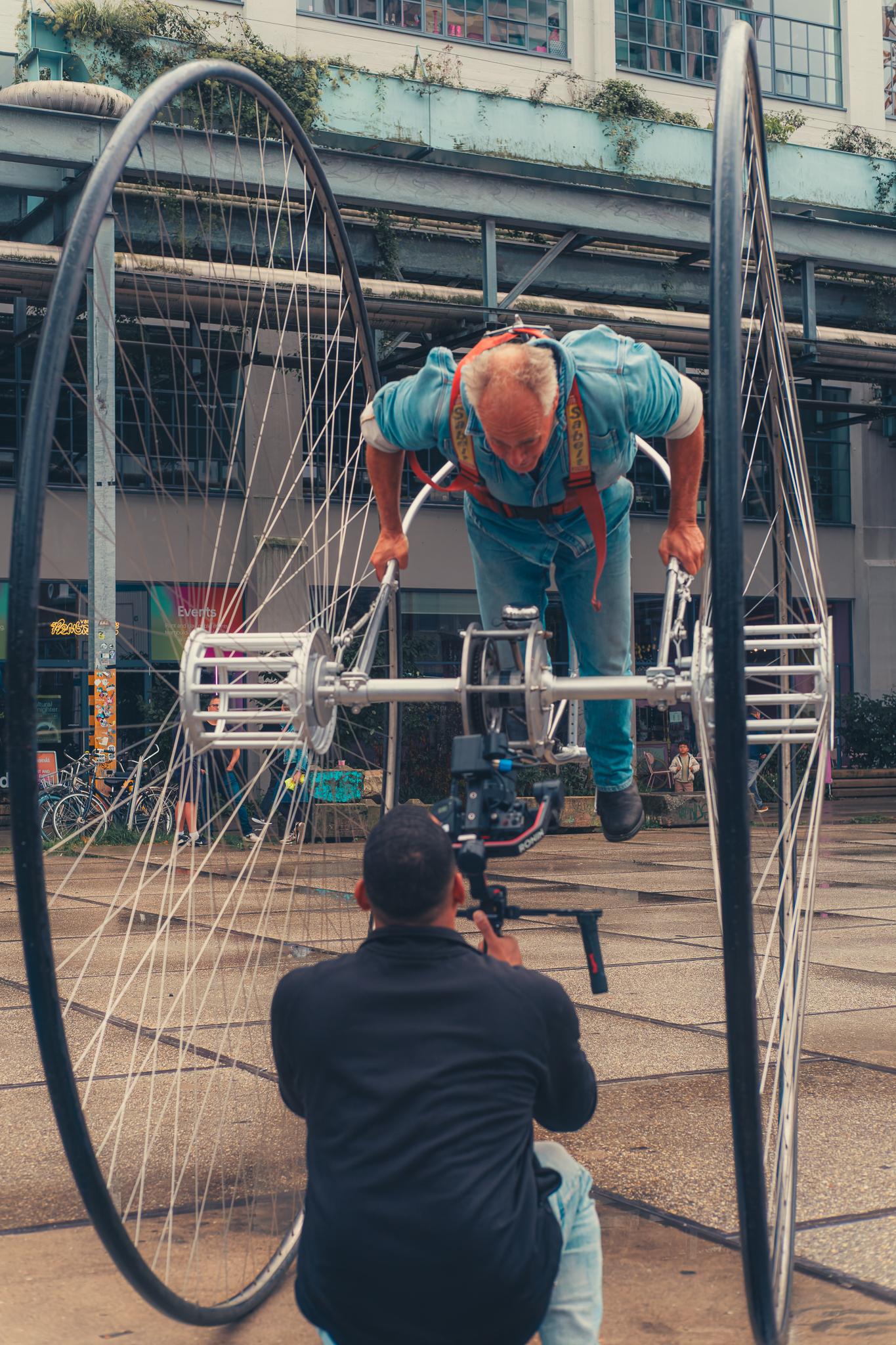 A performer inside a giant wheel rig being filmed with a handheld gimbal camera
