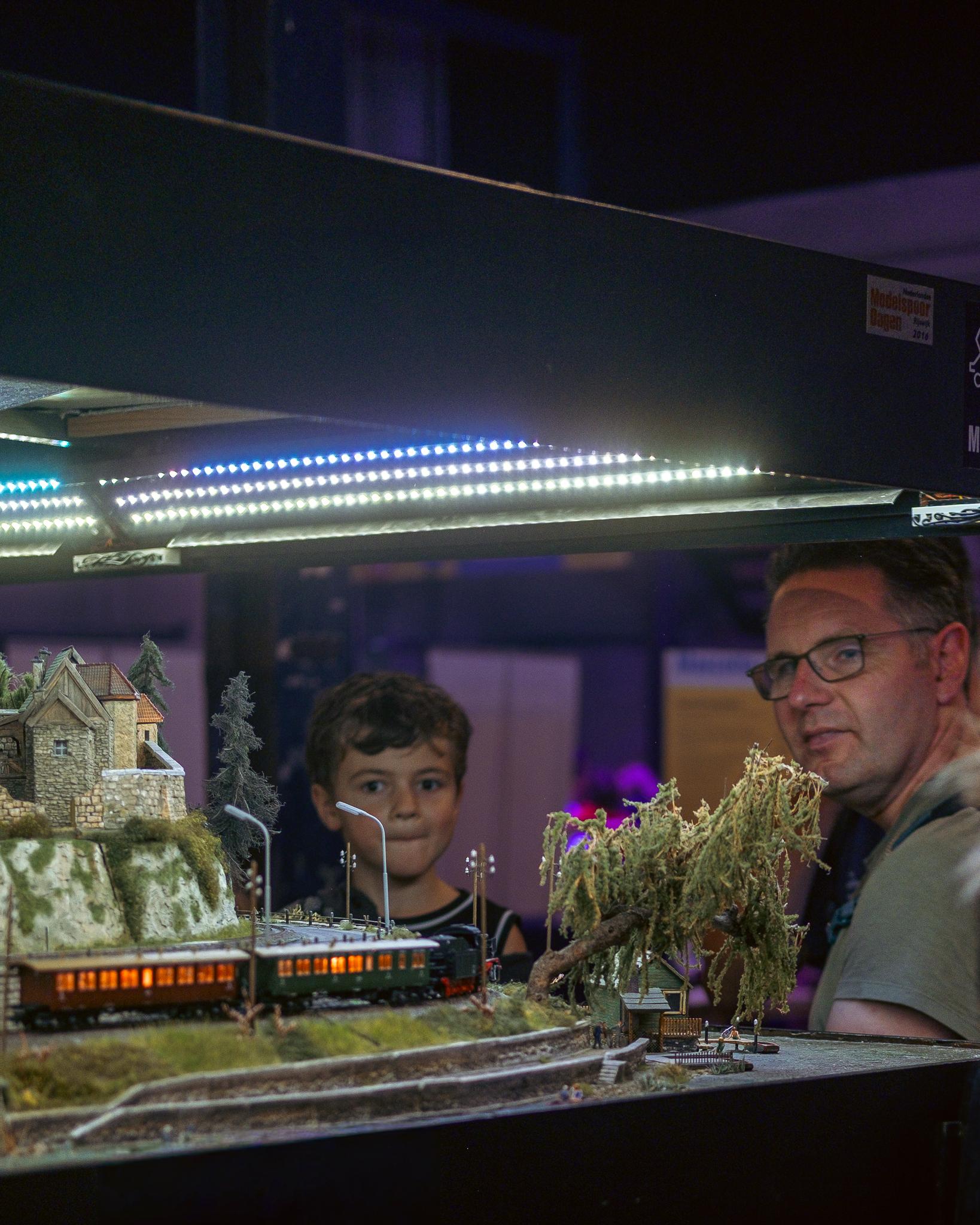 A father and son looking at a lit-up model railway diorama at Maker Days Eindhoven